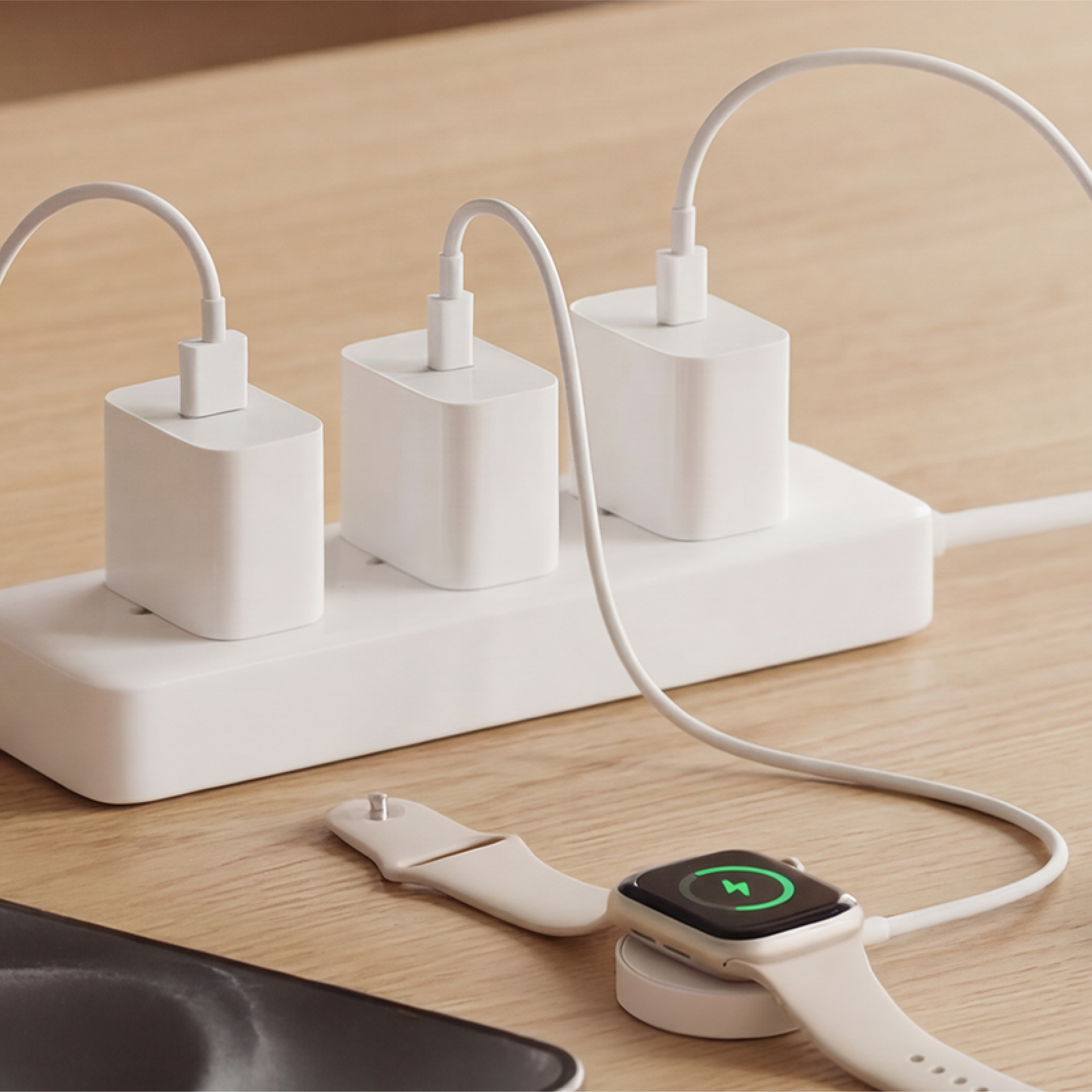 Multiple electronic devices connected to a power strip on a wooden surface
