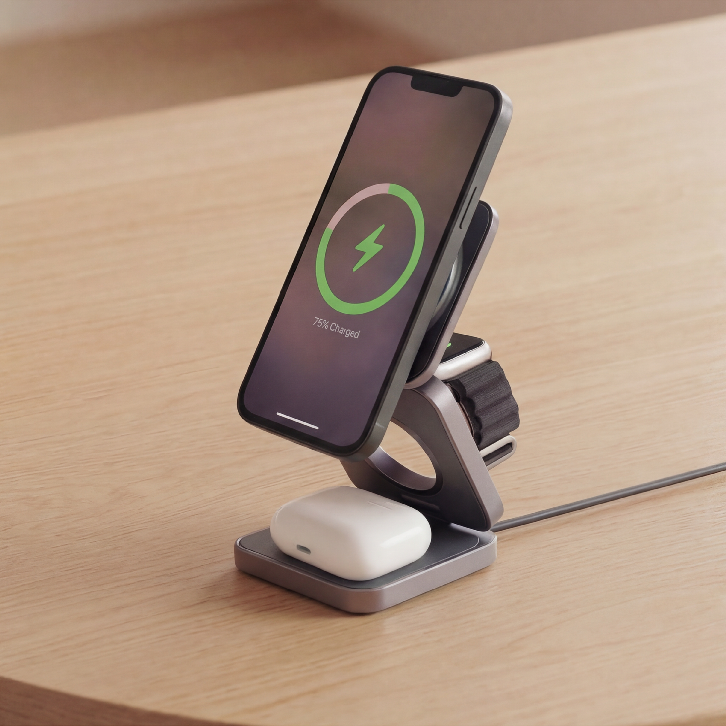 Smartphone, watch, and airpod on a wireless charging stand on a wooden surface